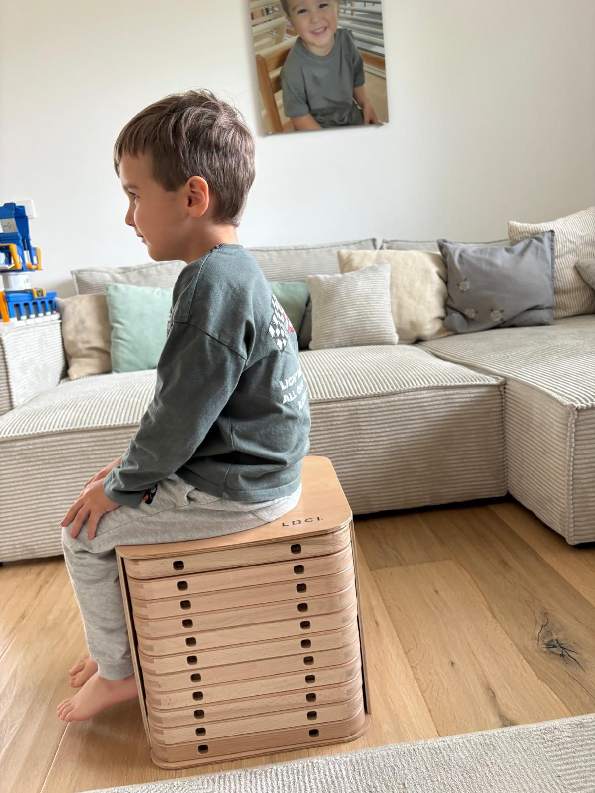 Ein Kind sitzt auf der LOCI-Box, die als Hocker dient